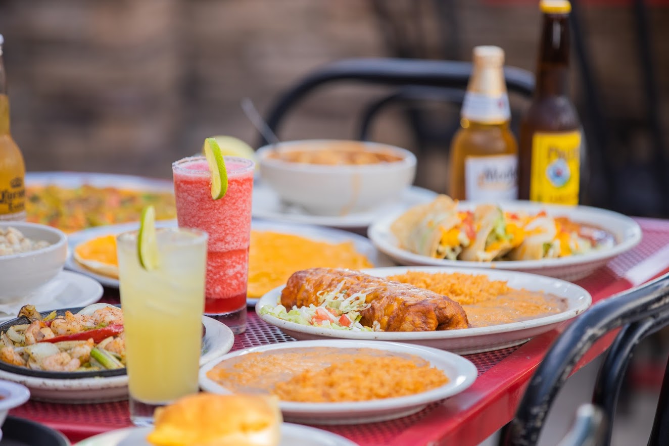 Various dishes on the table, margaritas and beer bottles